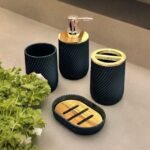 Bathroom soap dispenser set in black with toothbrush holder, soap holder and cup in black and gold.
