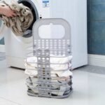 Portable laundry basket in dark grey next to washing machine.