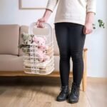 Woman using laundry basket to move towels and teddy bears for cleaning.