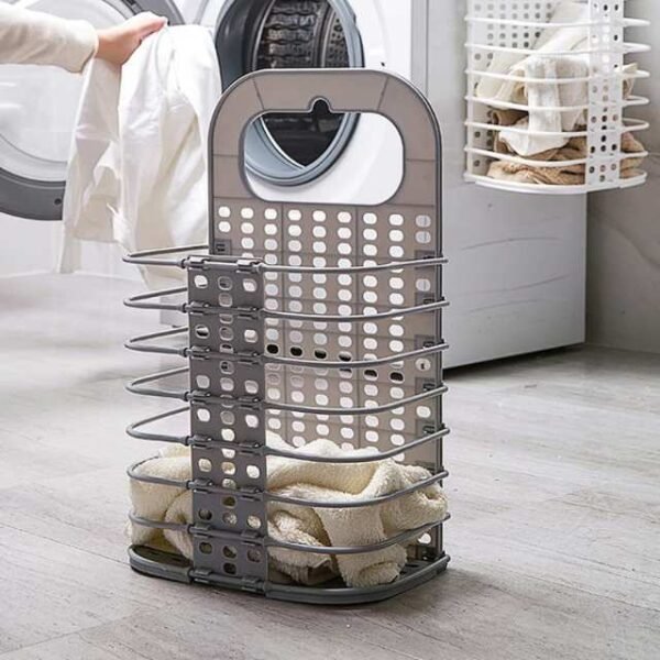 Portable laundry basket in black next to washing machine with dirty clothes inside.