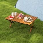 Aluminum camping table with wooden finish placed in the garden for outdoor picnics.