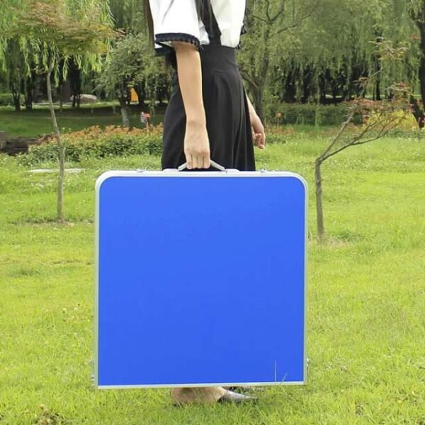 Woman effortlessly carrying compact picnic table set outdoors.