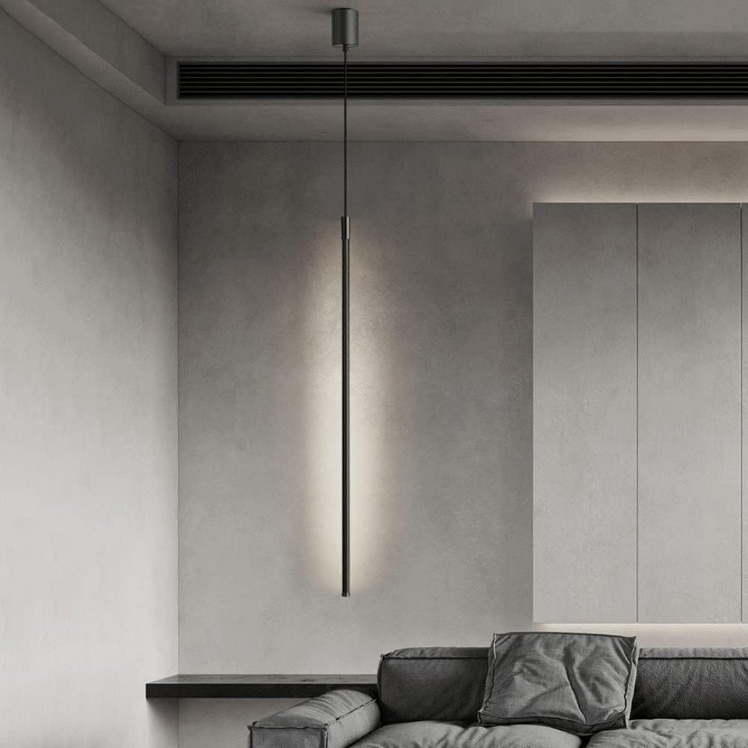 Slim pendant light in classic black illuminating a living room with warm LED light.