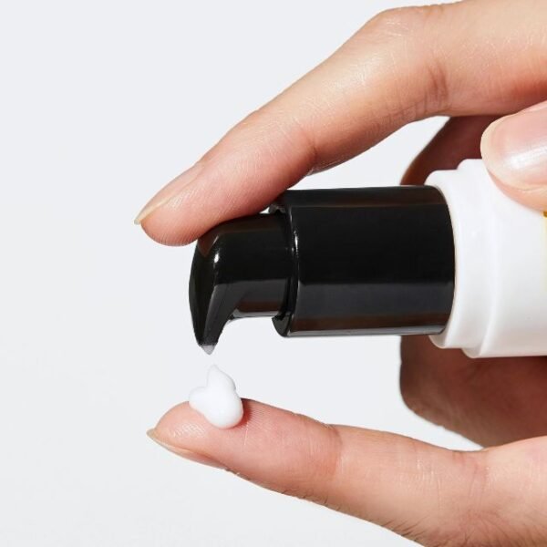 Woman dispensing COSRX under eye cream onto her finger for application.