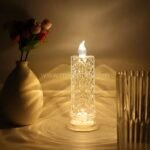 Crystal LED candle lamp with warm light and textured body, surrounded by decorative items.