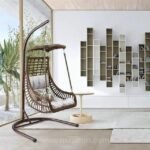 Hanging brown egg chair in living room with light grey cushion and handcrafted rattan design.