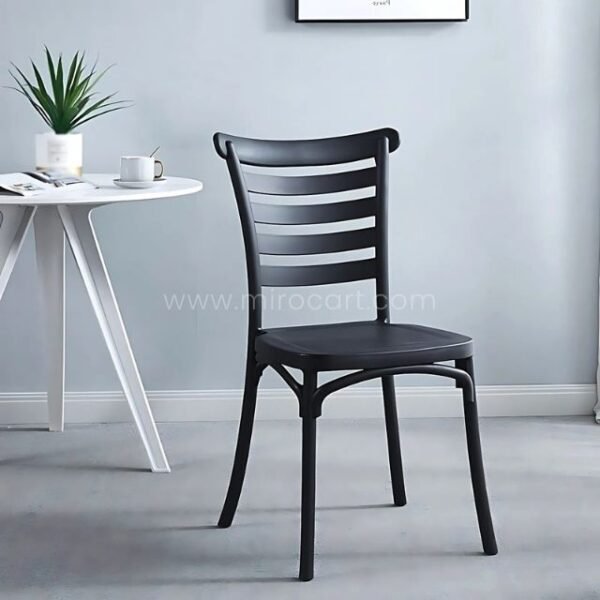 Black minimalist Nordic dining chair at a round white table in a modern space with a potted plant and contemporary decor.