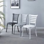 Three minimalist Nordic dining chairs in black, gray, and white side by side in a contemporary room with framed art and a potted plant.