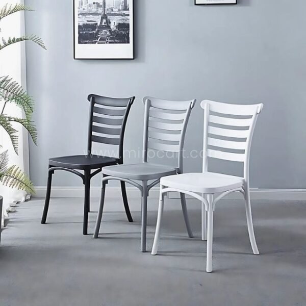 Three minimalist Nordic dining chairs in black, gray, and white side by side in a contemporary room with framed art and a potted plant.