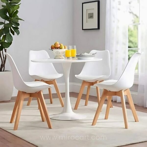 Four modern white dining chairs around a table in a kitchen setting.