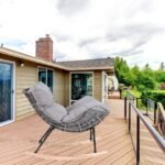 Rocking egg chair with rattan design, placed outside house overlooking garden.