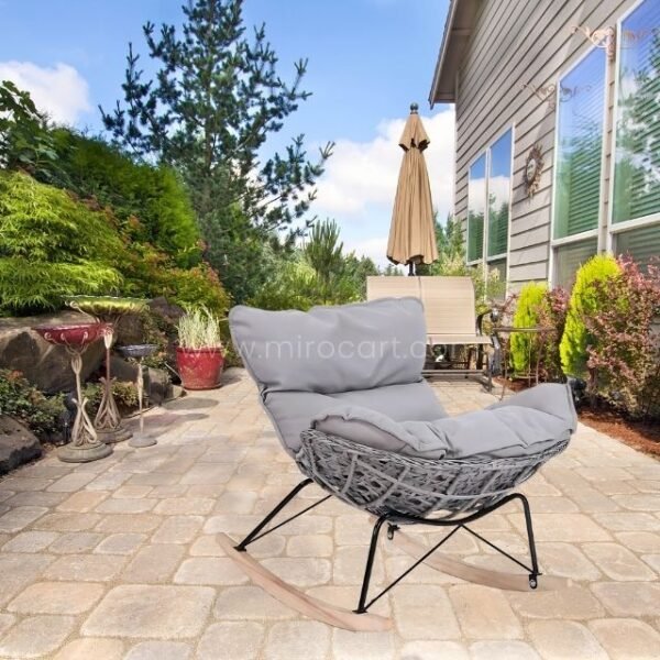 Rocking egg chair with handcrafted rattan and plush cushion in garden.