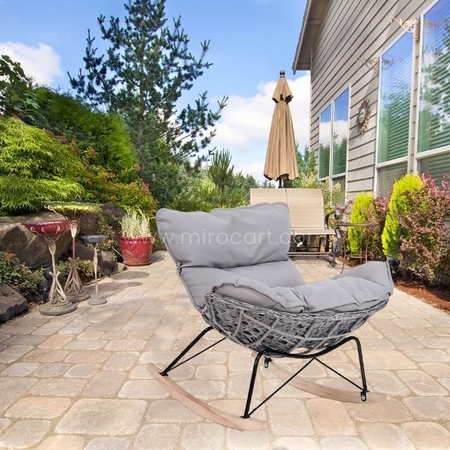 Rocking egg chair with handcrafted rattan and plush cushion in garden.