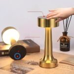Woman adjusting the brightness of the minimalist golden table lamp with a tap.