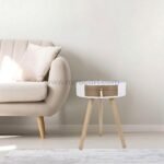 Modern bedside table beside beige tufted sofa in living room.