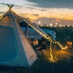 A campsite at dusk illuminated by solar string lights, creating a warm and inviting outdoor experience.