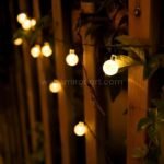 Solar-powered globe string lights elegantly draped over a wooden trellis, enhancing garden decor.