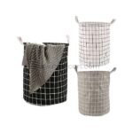 Three foldable laundry bags in grey, white, and black, neatly displayed in a minimalist room.