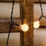 Cozy warm white string lights wrapped around rustic wooden beams, adding a charming glow to any outdoor space.