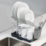 Neatly arranged 2-tier dish rack by sink with plate slots and cutlery compartment.
