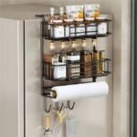 Two-tier fridge-mounted spice rack organizing jars of spices, oils, and baking essentials with a paper towel holder and tool hooks.