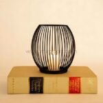 Oval black lantern candle holder on a classic hardcover book.