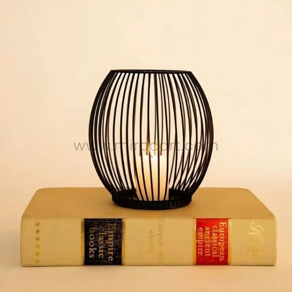 Oval black lantern candle holder on a classic hardcover book.