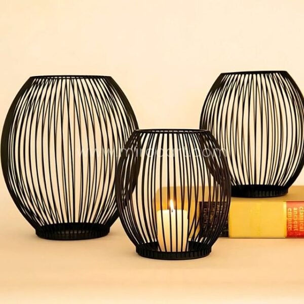 Black spherical lanterns of different sizes beside stacked books.