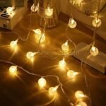 Globe string lights arranged on wooden surface, casting warm white glow.
