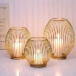 Three gold lantern candle holders with lit white candles creating warm ambiance through vertical wire design.