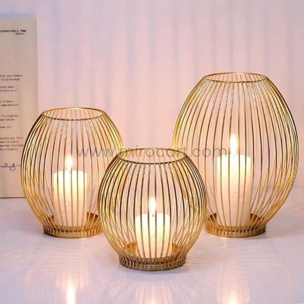 Three gold lantern candle holders with lit white candles creating warm ambiance through vertical wire design.