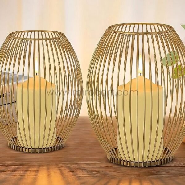 Two gold lantern candle holders glowing beside books and greenery.