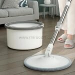Hands-free spin mop with a flat head and white bucket on a tiled kitchen floor, showcasing its practicality for mess-free cleaning.