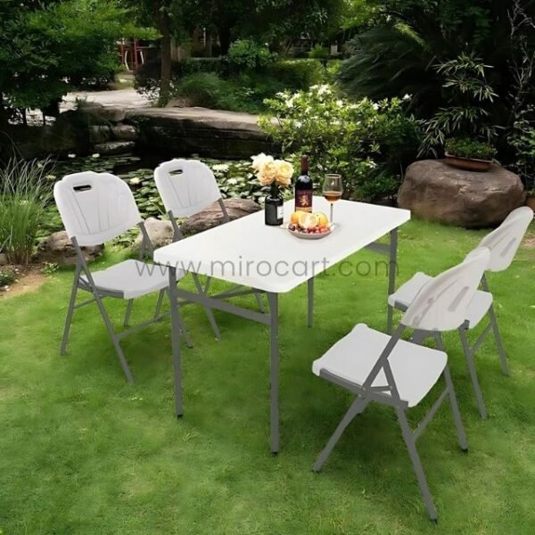 Folding chairs set around a table outdoors, surrounded by greenery. Ideal for relaxing meals or gatherings.