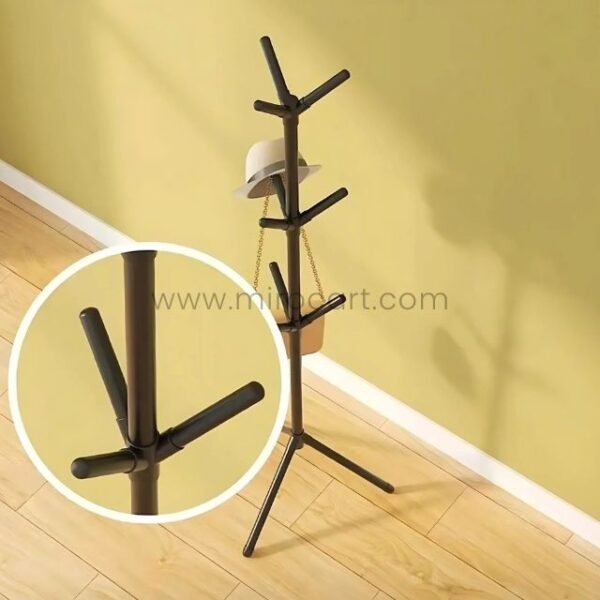 Tree branch coat hanger holding a hat and bag against a yellow wall.