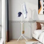 White tree branch coat hanger holding clothes in a bedroom with paneled walls.