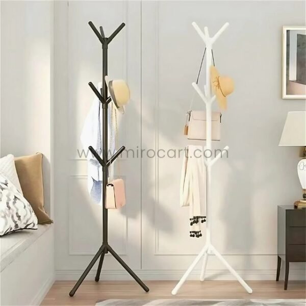 Black and white minimalist tree branch coat hangers holding accessories in a stylish bedroom.