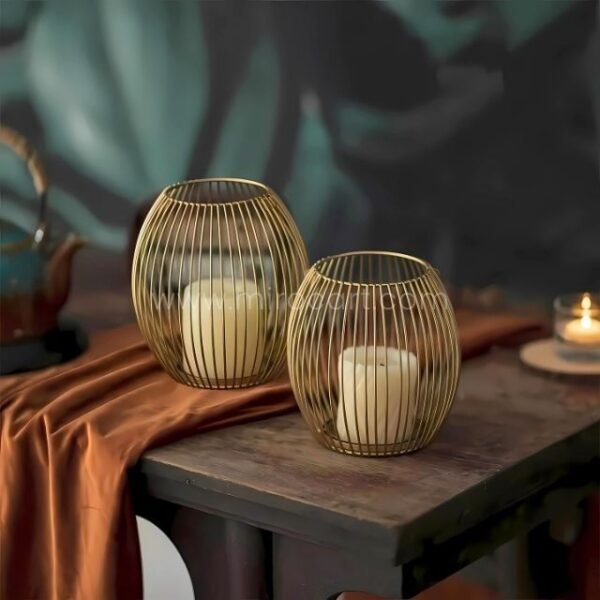 Gold lantern candle holders on wooden table with rustic fabric and teapot.