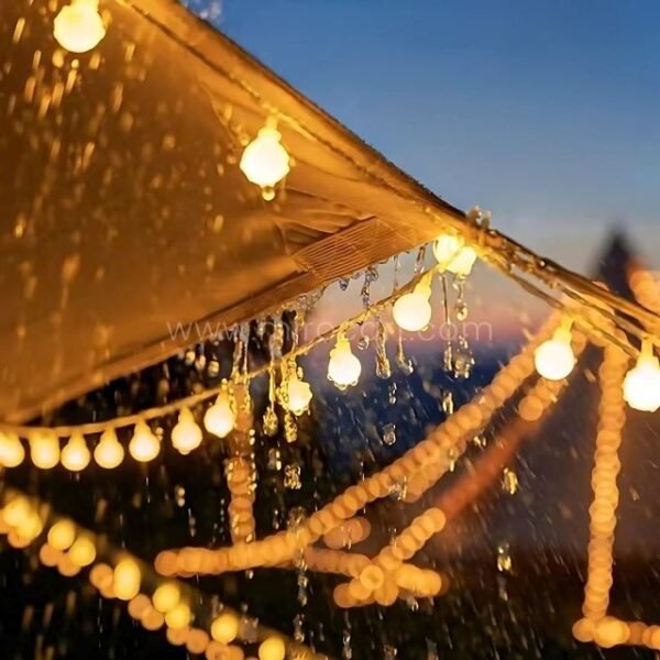 Waterproof globe string lights glowing under canopy in rainy weather, creating a cozy outdoor atmosphere.