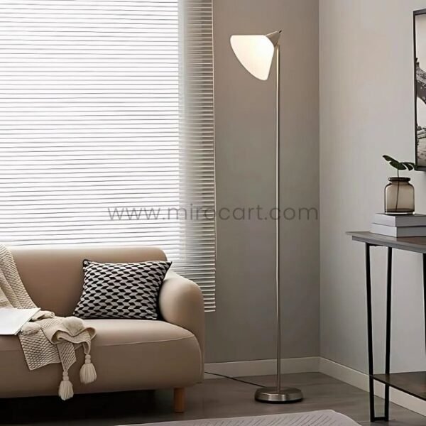 Adesso Swivel Floor Lamp with a sleek chrome finish and white triangular shade, placed beside a cozy beige sofa in a modern living room.
