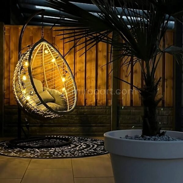 Grey rattan egg chair under twinkling fairy lights on evening patio, creating magical ambiance