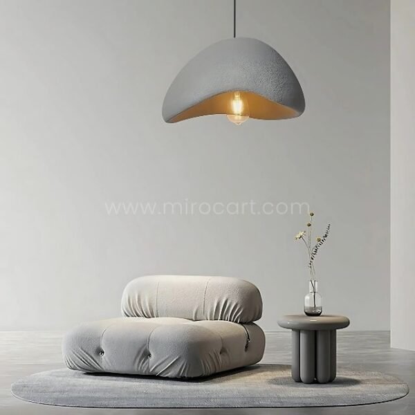 A Creative Wabi-Sabi Pendant Lamp illuminates a tranquil living area, adding warmth and simplicity to the space.