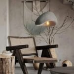 A Creative Wabi-Sabi Pendant Lamp with a textured gray shade casts a warm, inviting glow over a cozy living area filled with natural textures.