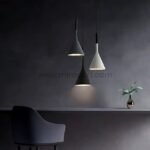 Three Nordic Cone Pendant Lamps in gray, black, and white suspended in a dimly lit room with a vase of flowers on a table.