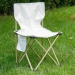 Lightweight easy-fold camping chair with beige fabric and steel frame on grass