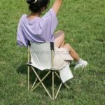 Woman enjoying nature in beige easy-fold camping chair.