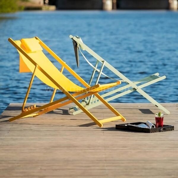 Two foldable beach sun loungers set up on a lakeside dock at sunset.