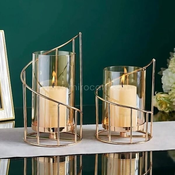 Golden pillar candle holders reflecting light dramatically on black polished surface.