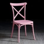 Blush pink cross-back chair with delicate charm.