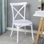 White cross-back chair at a table set for dinner.